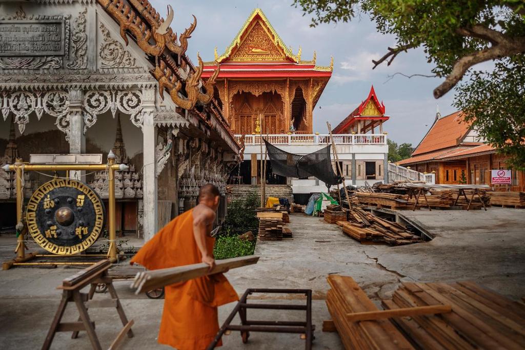 Vid det nya templet syns munken Phra Amnuay bära några träplankor till byggnadsarbetarna på plats. (Bild: Jonas Gratzer)